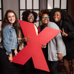 Four volunteers holding up a large red X while smiling